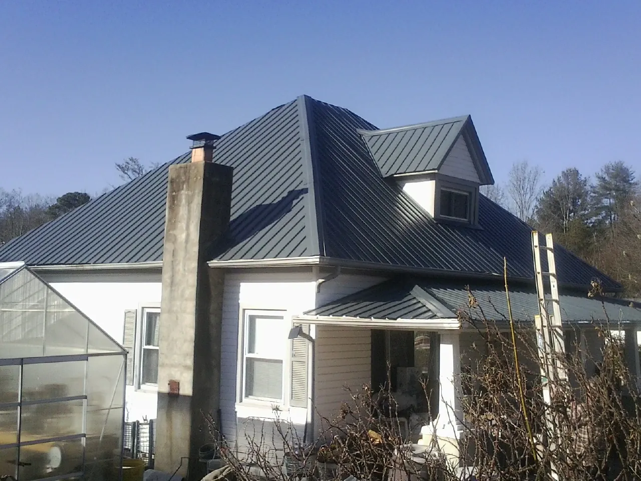 Dark blue standing seam metal roof on a white farmhouse with dormer — Slate & Tile Roof Repair by Roofing Brothers in Edinburgh