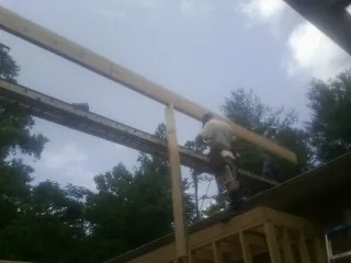 Carpenter setting a ridge beam over a new addition frame — Ice Dam Removal by Roofing Brothers in Edinburgh