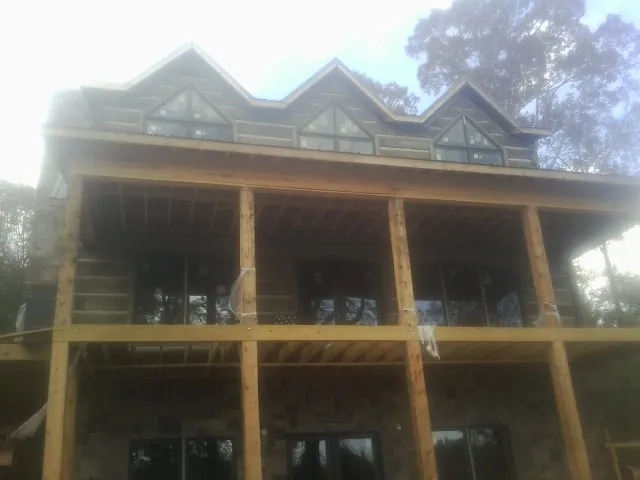 Dormers and porch framing on a large log home under construction — Roof Coating work by our crew in Edinburgh