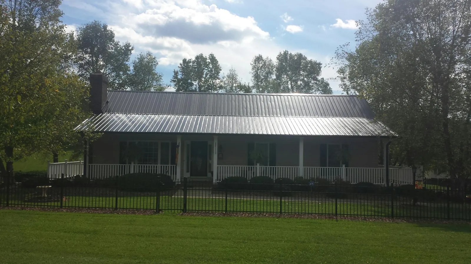 Gray metal roof on a brick ranch with a full width front porch — Gutter Guard Installation work by our crew in Edinburgh