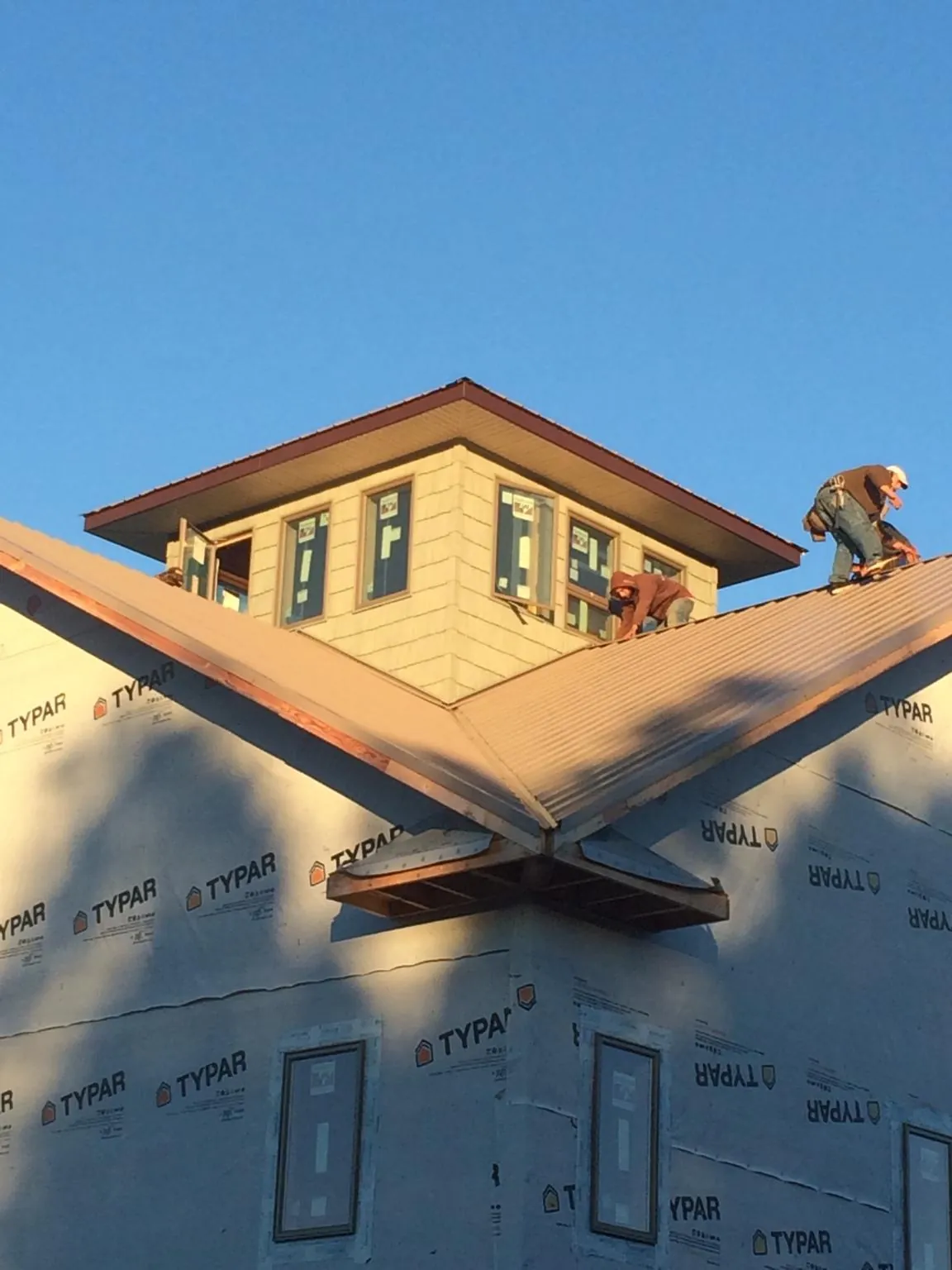 Roofers working around a rooftop cupola on a new metal roof at sunset — Roof Waterproofing in Edinburgh by Roofing Brothers